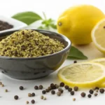 Bowl of lemon pepper seasoning with fresh ingredients in the background.