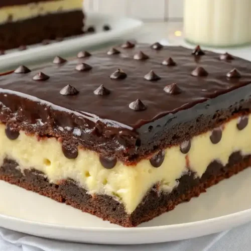 A beautifully presented Boston Cream Poke Cake with layers of vanilla cake, creamy pudding, and chocolate glaze.